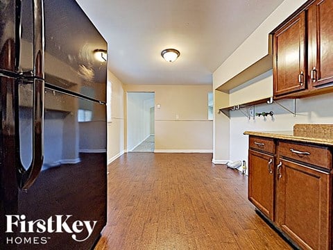 a kitchen and a living room with wood floors and a stainless steel refrigerator