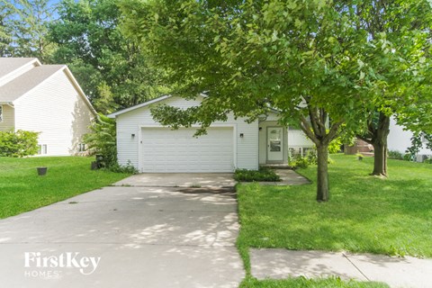 a white house with a driveway and trees in front of it
