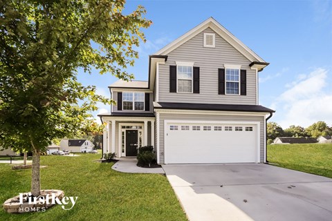 a gray house with a white garage door and a tree