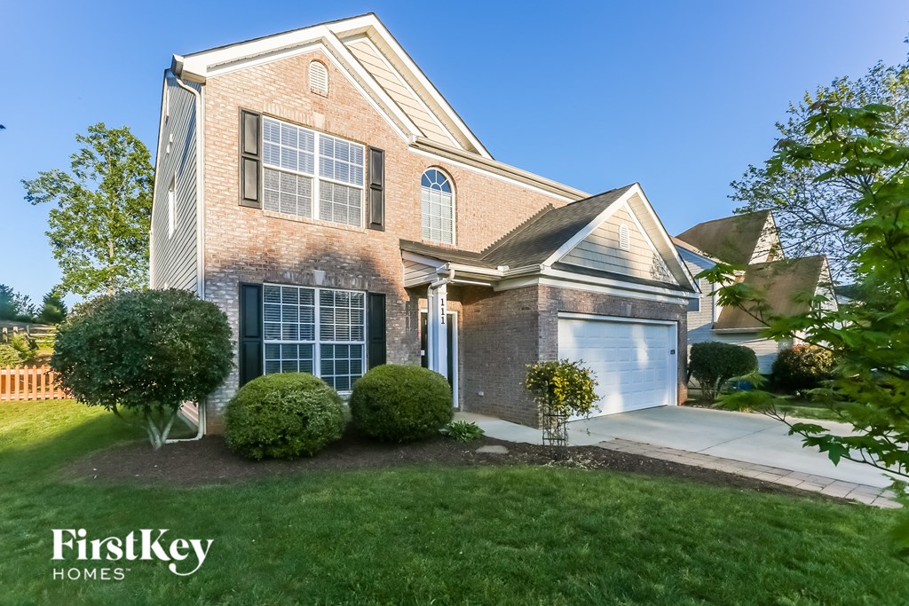 the front of a brick house with a white garage door
