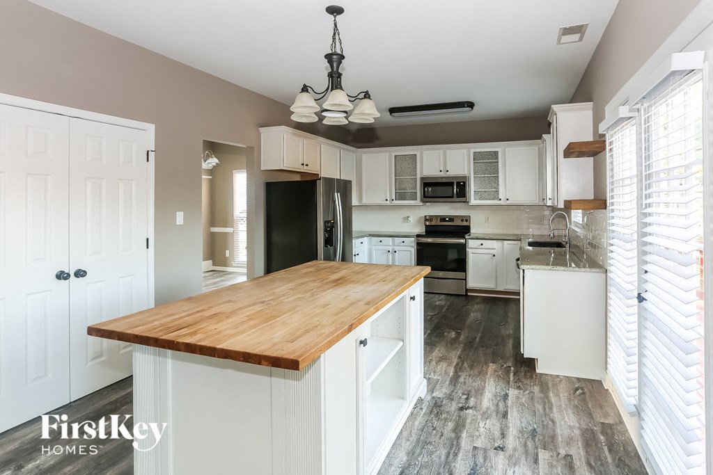 a kitchen with white cabinets and a wooden counter top