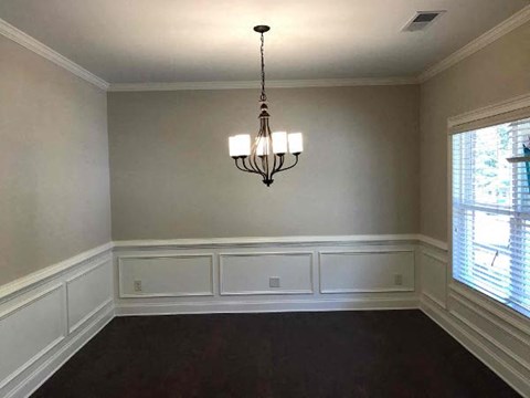 a empty dining room with a chandelier and a window