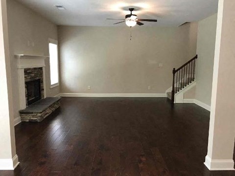 a empty living room with a ceiling fan and a fireplace