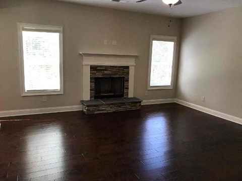a empty living room with a fireplace and wooden floors