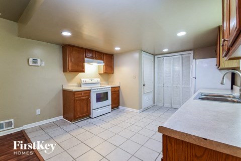 A kitchen with a white tile floor and a white stove top oven.