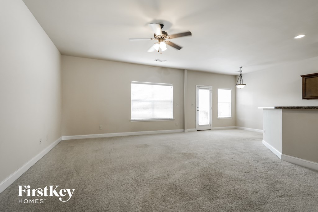 an empty living room with a ceiling fan and a window