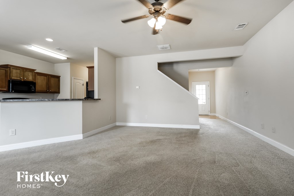 an empty living room and kitchen with a ceiling fan
