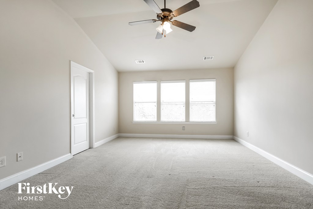 an empty room with a ceiling fan and a window