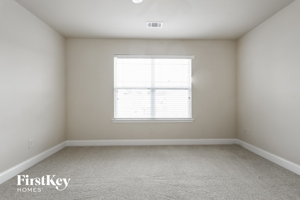 a bedroom with white walls and a window