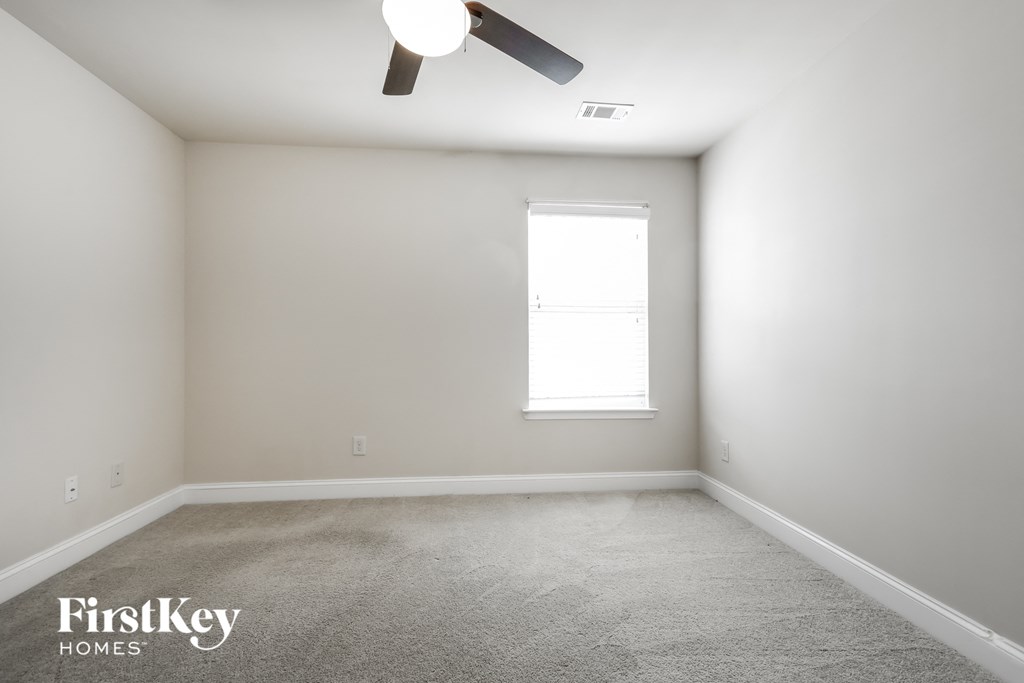 a empty room with a ceiling fan and a window
