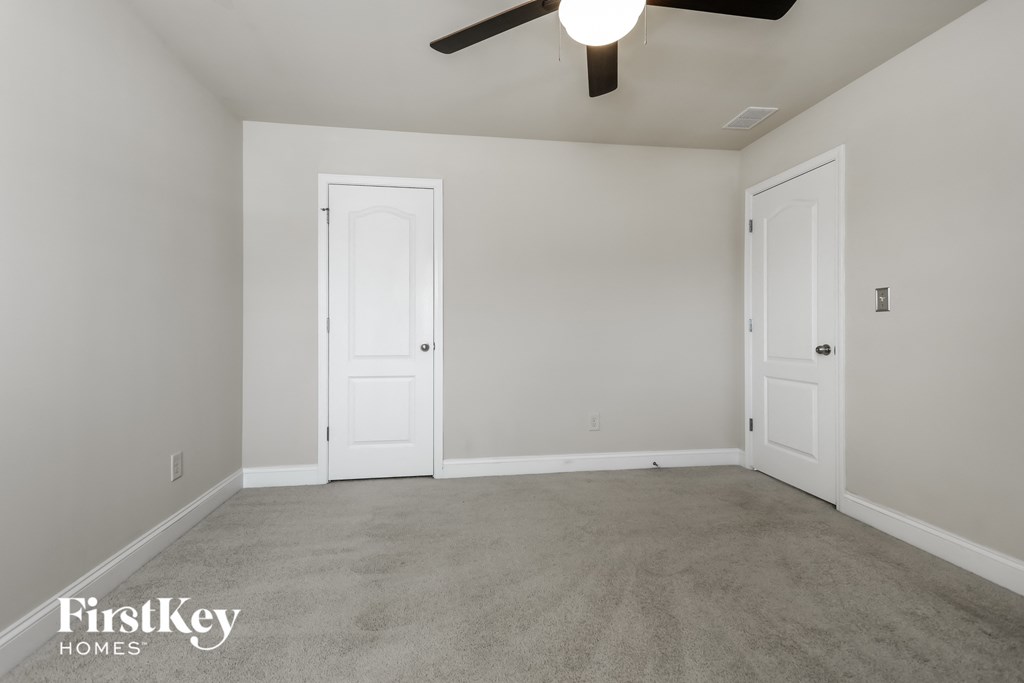 a empty living room with two doors and a ceiling fan