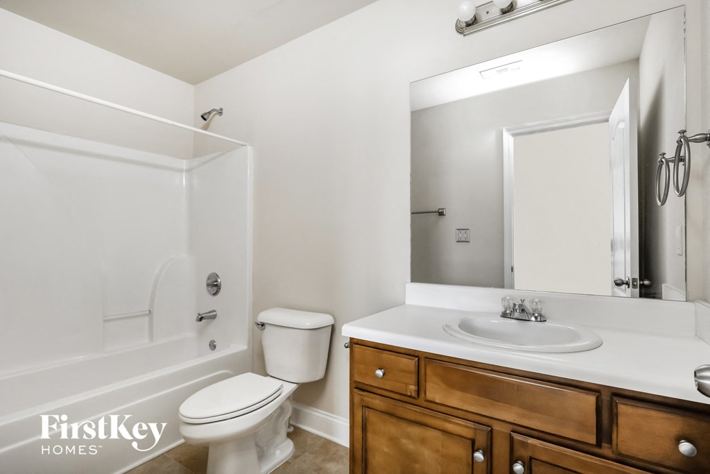 a bathroom with a toilet sink and shower and a mirror