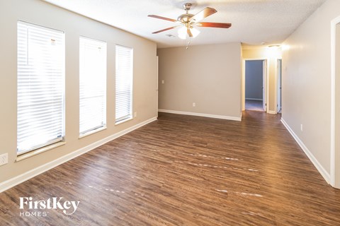 the living room and dining room with wood flooring and a ceiling fan