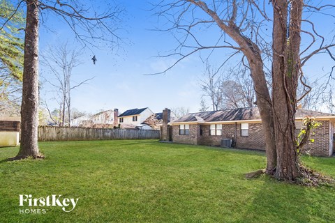 a backyard with two trees and a brick fence