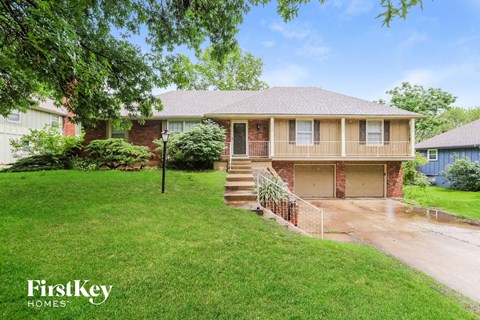 a small brick house with a yard and a driveway