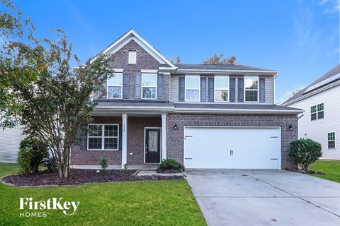A house with a garage and a tree in front of it.