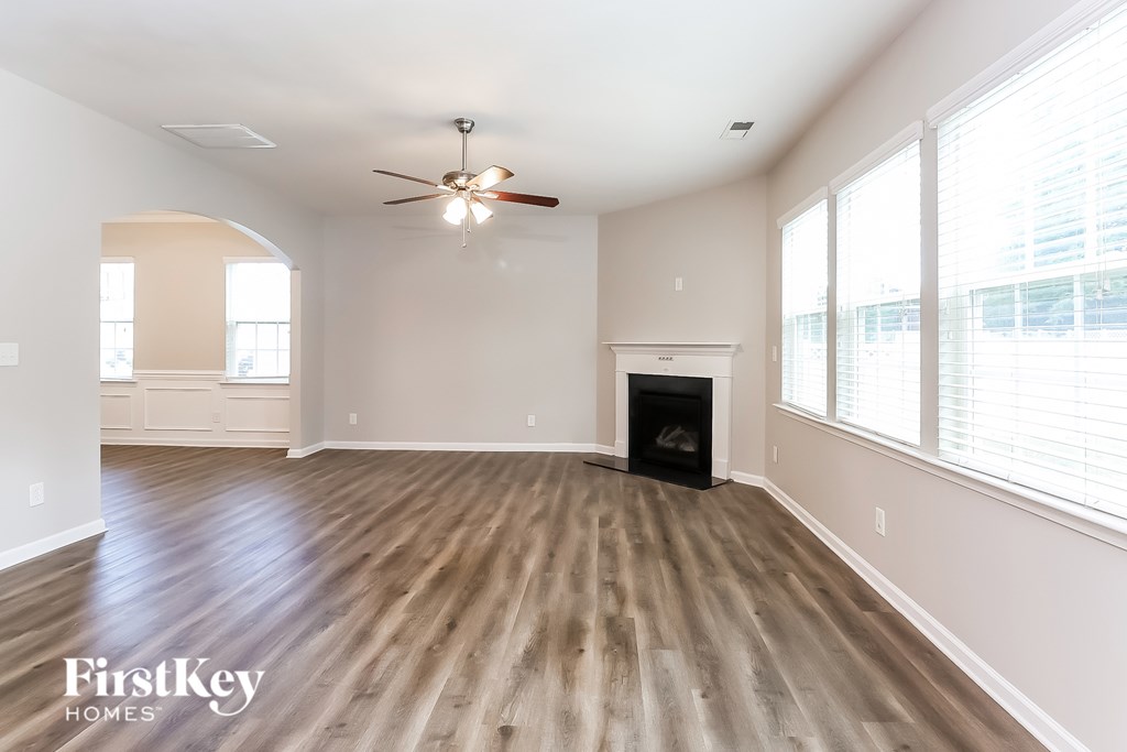 A spacious room with wood flooring and a ceiling fan.