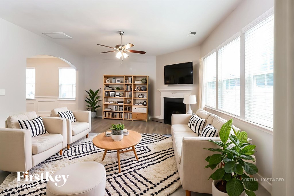 A living room with a white couch, a coffee table, and a ceiling fan.