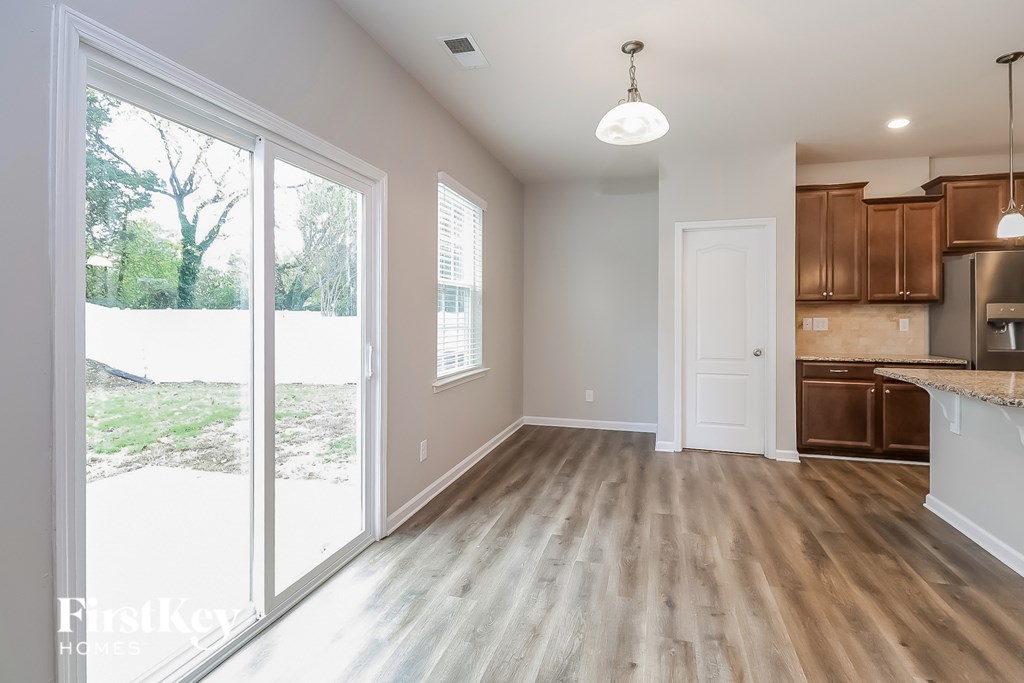 A spacious room with wooden floors and a kitchen area with brown cabinets.