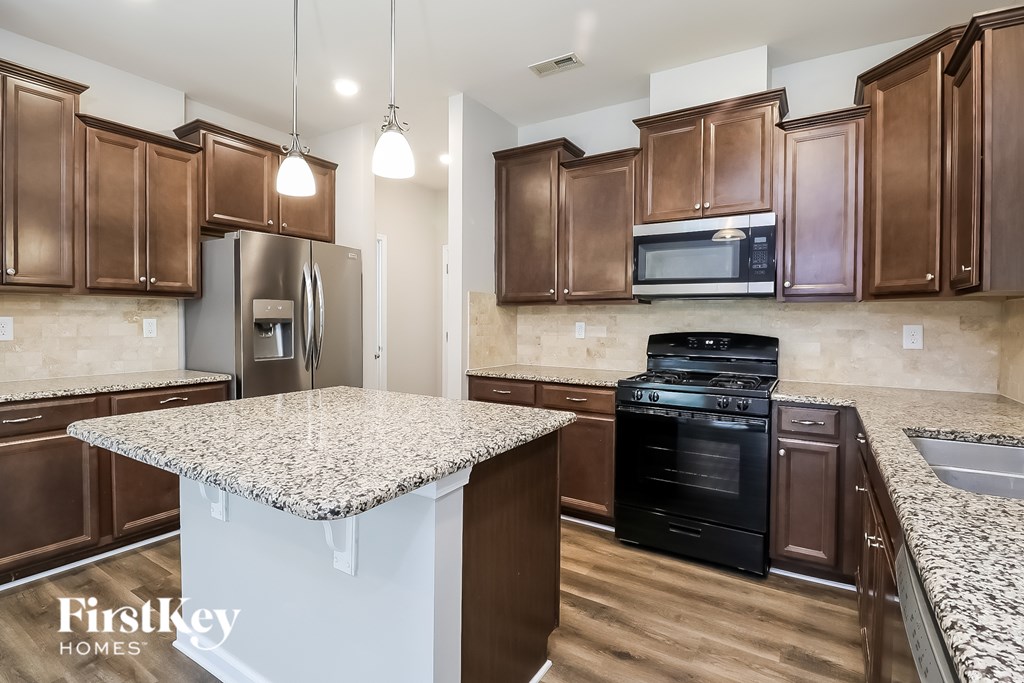 A kitchen with brown cabinets and a granite countertop.