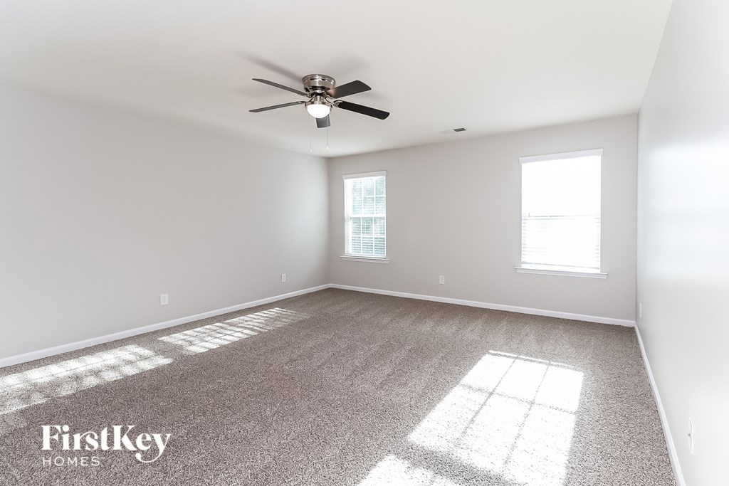 A room with a fan and two windows.