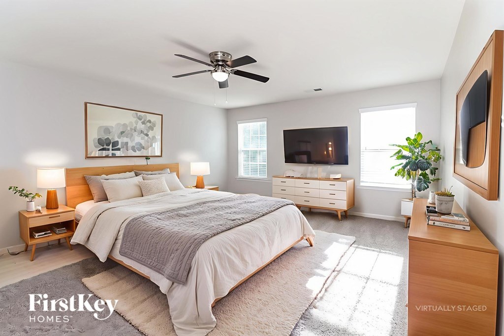 A bedroom with a large bed, a ceiling fan, and a television.