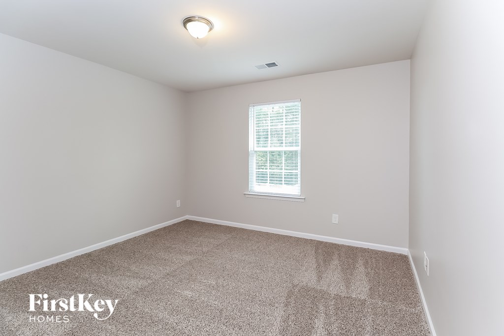 A room with a carpeted floor and a window with blinds.