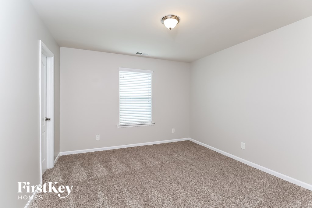 A room with a carpeted floor and a window with blinds.