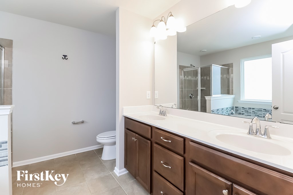 A bathroom with a toilet, sink, and mirror.
