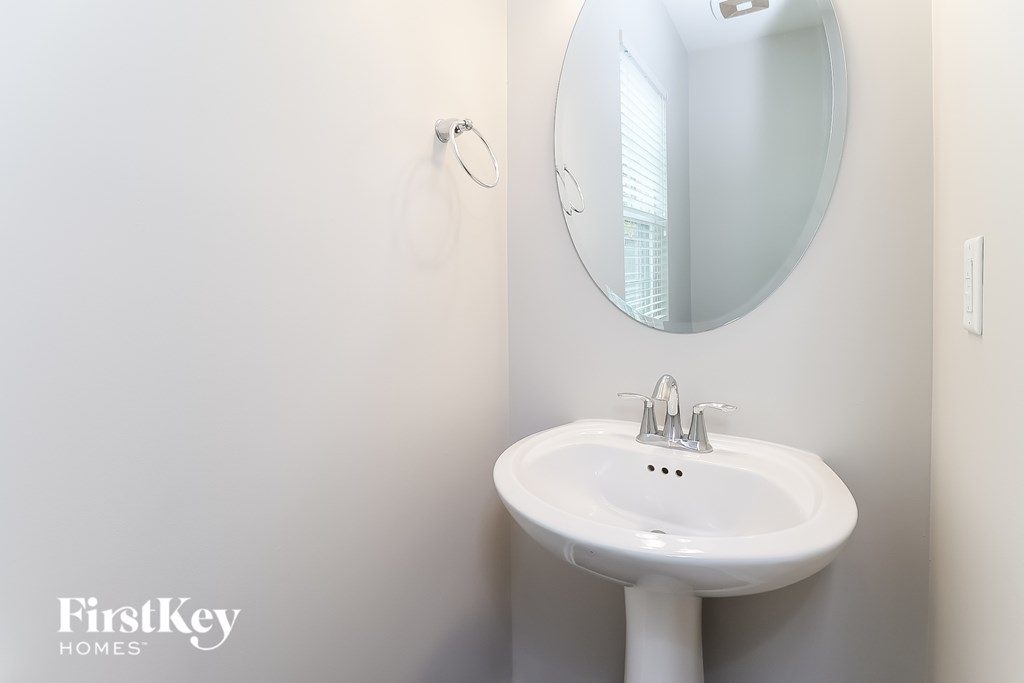 A white sink in a bathroom with a round mirror above it.