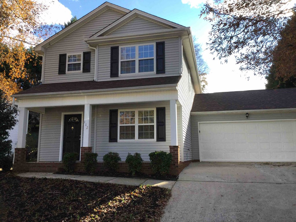 A house with a grey siding and a white garage door.