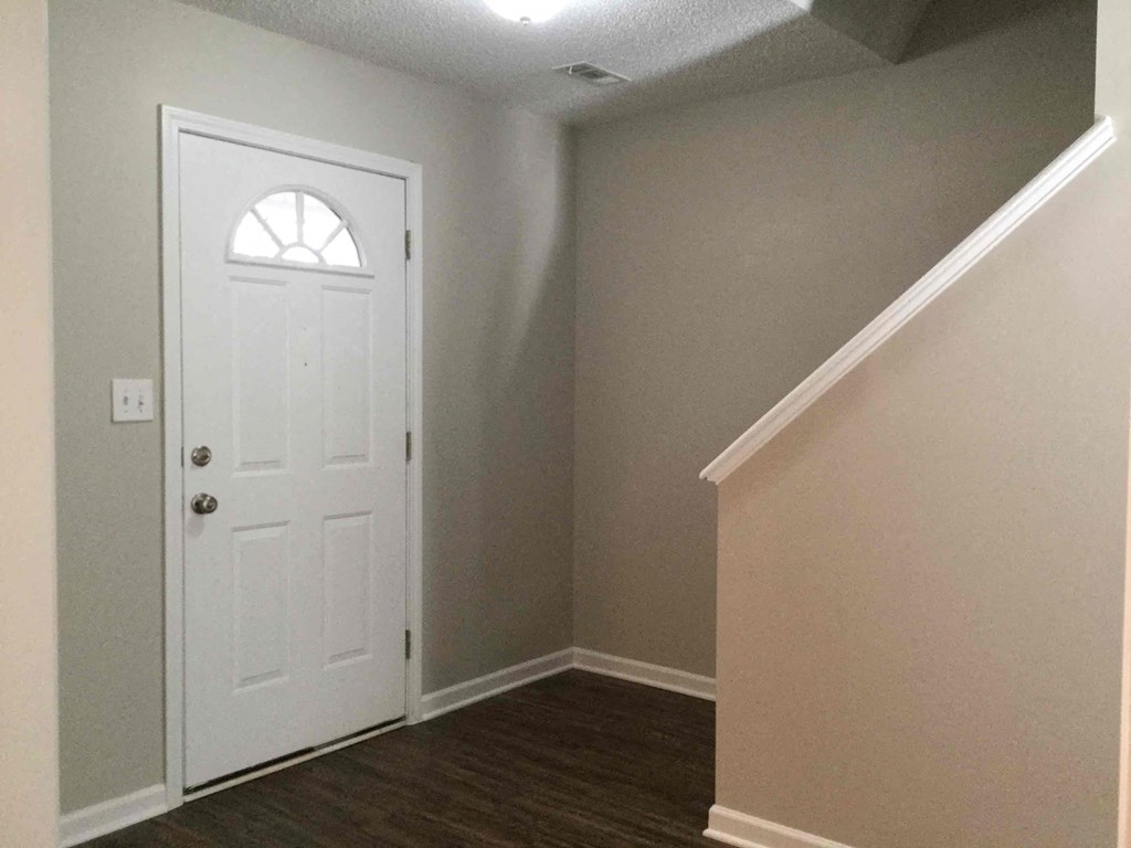 A white door with a window in the center is in a room with a wooden floor.