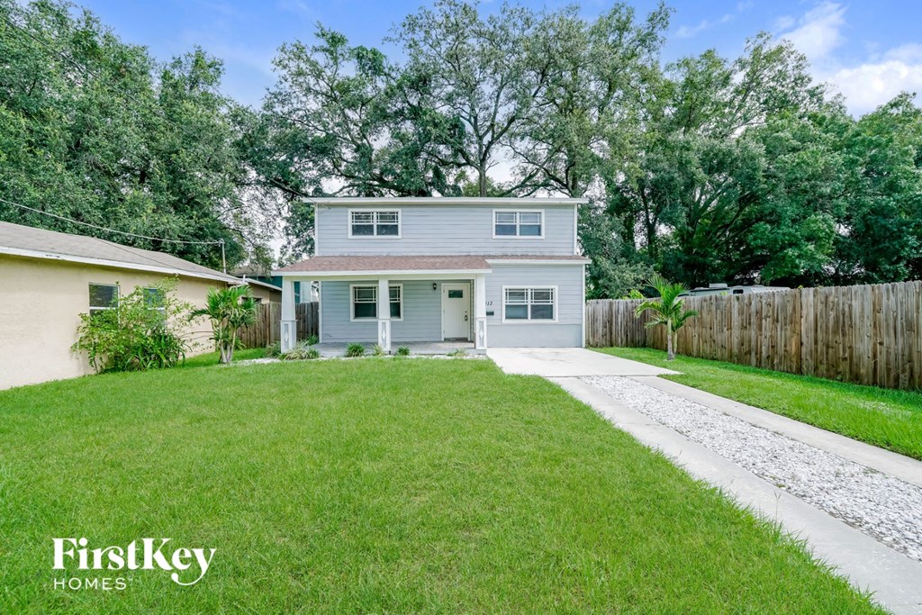 a blue house with a lawn and a driveway
