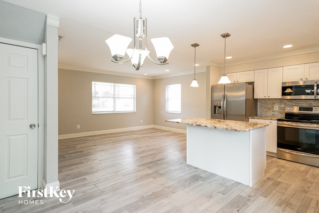 an open kitchen and dining room with white cabinets and a marble counter top