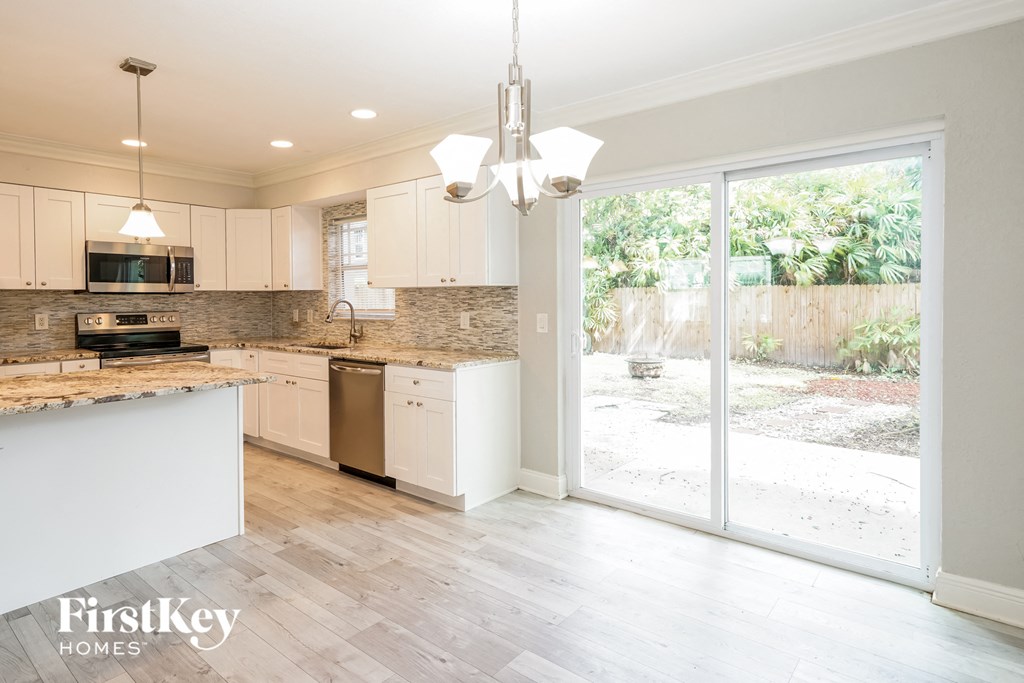 a kitchen with white cabinets and a sliding glass door