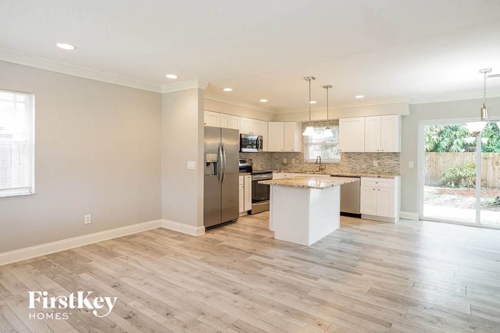 a kitchen with a large island and a stainless steel refrigerator