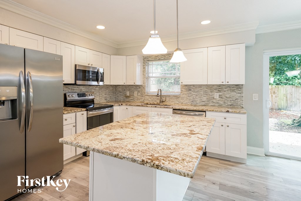 a kitchen with white cabinets and a marble counter top