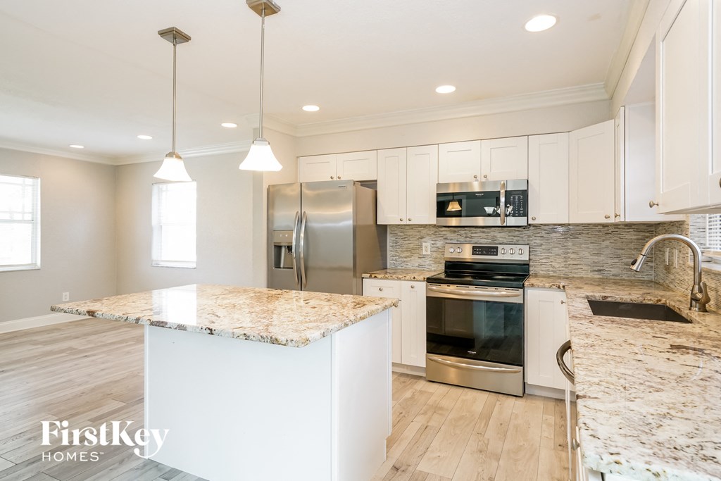 a white kitchen with marble counter tops and stainless steel appliances