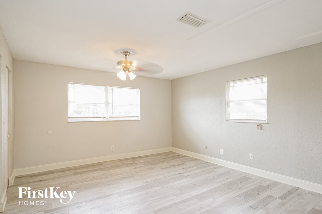 a bedroom with white walls and wood floors and a ceiling fan
