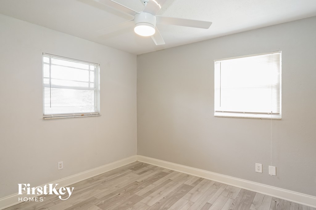 a bedroom with wood flooring and a ceiling fan