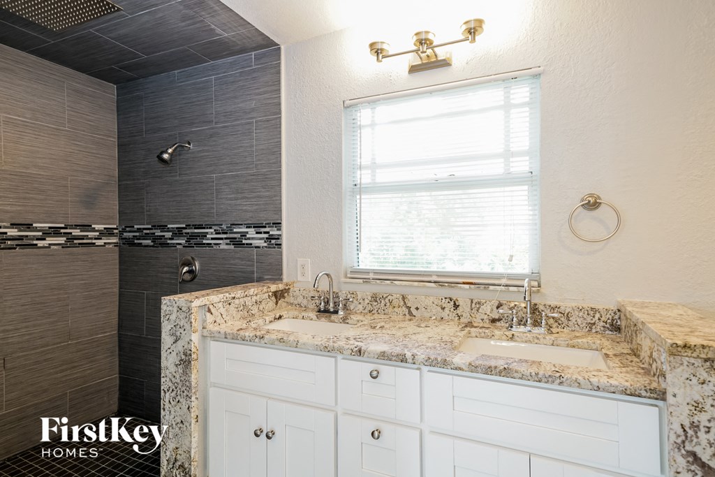 a bathroom with a sink and a shower and a window