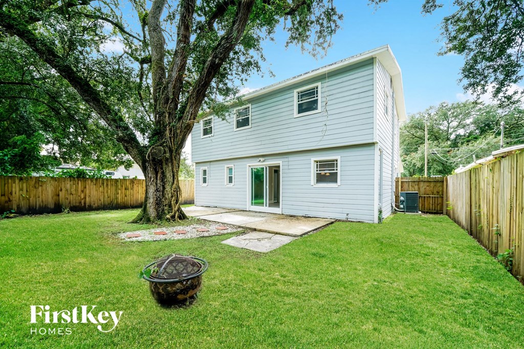 a backyard with a white house and a large tree