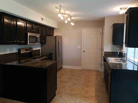 A kitchen with black cabinets and a brown countertop.