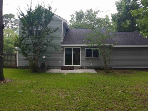 A house with a grey siding and a black roof with a small porch.
