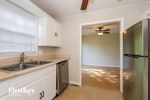 a kitchen with white cabinets and a sink and a refrigerator