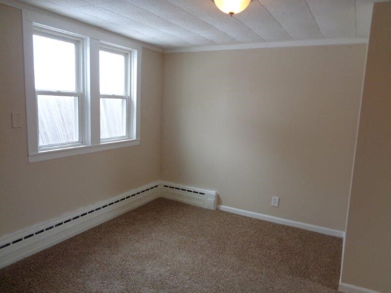 A room with a window and carpeted floor.