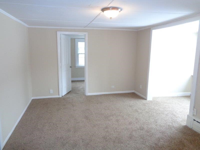 A room with a carpeted floor and a doorway leading to another room.