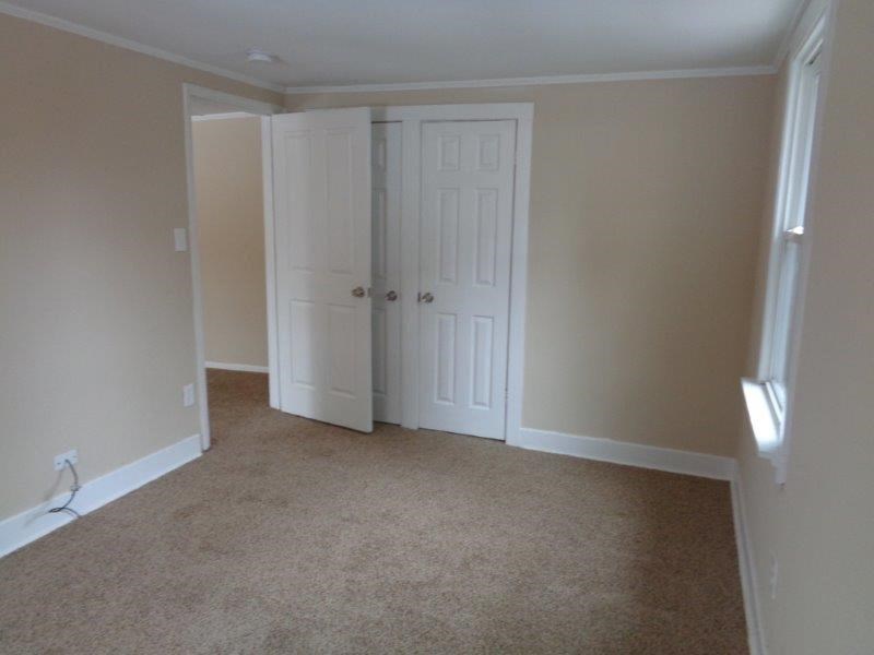 A room with a carpeted floor and two white doors.