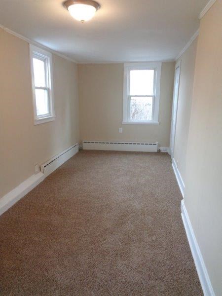 A room with carpeted floor and two windows.