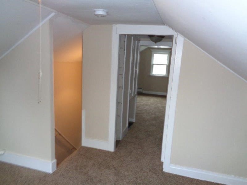 A hallway with a carpeted floor and white walls.